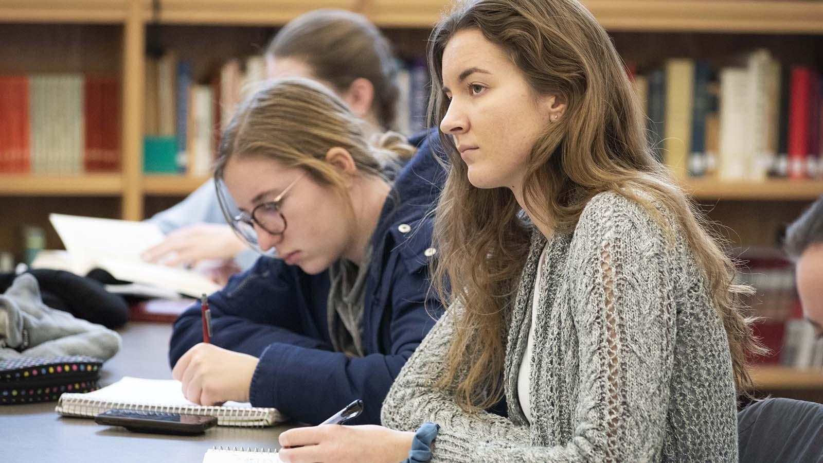 Female students listening to lecture in Catholic studies classroom